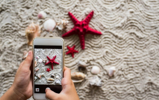 un teléfono móvil le hace una foto a una estrellita de mar roja